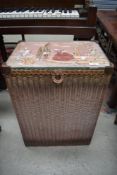 A Lloyd Loom linen basket in pink with crinoline lady decoration to top