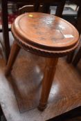 A tri legged stool, having horse carving to top