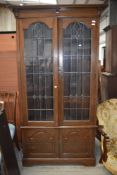 An early 20th Century narrow bookcase, having glazed section with leaded doors in the Art Nouveau