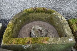 A large farm house style stone carved half moon water trough or feeder with cast plug
