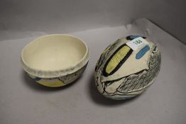 Two items of textured studio pottery in blue and yellow tones on natural ground, both marked KB to