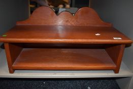 A wooden wall shelf having scalloped ledge back.