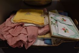 A box full of vintage and retro table and bed linen including boxed napkin and tray cloth set.