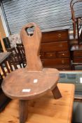 A Wanderwood Arts and Crafts elm three legged stool, with label to underside, damage to one leg