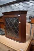A Victorian mahogany small wall cabinet having mottled leaded glass door