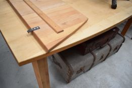 A large modern pine dining table, of shaped rectangular form with end extensions, and raised on