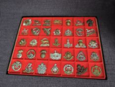 A display tray of Thirty Five metal Military Cap Badges including South Wales Borderers, Kings