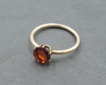 A small solitaire dress ring having a hessonite garnet style stone in a 6 claw setting on a rose