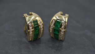 A pair of emerald and diamond stud earrings having a central row of baguette cut emeralds flanked by