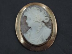 A large conch shell cameo brooch depicting a Grecian maiden in a rose gold plain collared mount