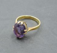An Oriental oval amethyst dress ring in a raised claw mount on a 14ct gold loop bearing possibly