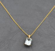 An aquamarine style pendant in a yellow metal mount on a yellow metal chain stamped 18K, approx