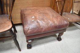 A reproduction leather footstool having cabriole legs with ball and claw feet