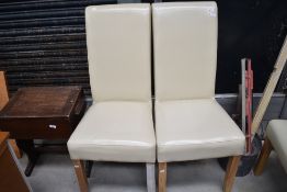 A pair of modern cream leatherette dining chairs
