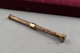 A 9ct gold propelling pencil, with sliding adjustment, having engraved decoration and inset purple