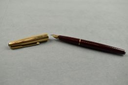 A Parker 65 fountain pen in burgundy with gold cap. Approx 13.4cm