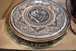 A group of four decorative metal plates, one brass with South American design and three of