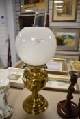 A brass based library or desk top oil lamp having milk glass shade