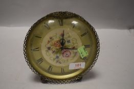 A mid century kitsch style clock having brass frame with embroidered center