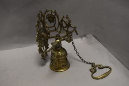 An antique brass wall mounted front door bell having drop chain with swinging bell