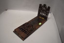 An Edwardian fold out extending book shelf having pierced flora sides