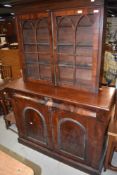 An early Victorian marriage of side board and astral glazed book case both having flame mahogany