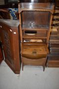 An early 20th Century oak stationery cabinet with shelf/drop flap and magazine section