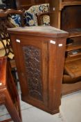 A 19th Century oak narrow corner cupboard having carved panel