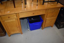 A modern solid pine office desk having drawer and cupboard storage with laptop drawer