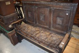 An 18th century and later oak settle, with rustic frame utilising a panelled 19th century bed head