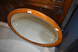 An early to mid 20th Century golden oak oval wall mirror