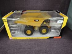 A Norscot 1:50 scale diecast CAT 793D Mining Truck in yellow in plastic packaging and in window