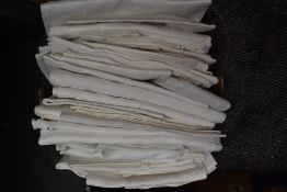 A box full of vintage and antique damask and linen table cloths and tray cloths.