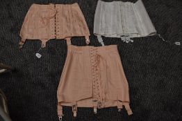 Three vintage boned girdles in pink and white having metal suspender clasps.