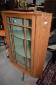 A 20th century golden oak corner cupboard having astral glazed door