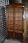 An early 20th century oak book case having leaded light doors with under cupboard