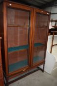 A late Victorian mahogany library book case having rolled glass doors on twist legs