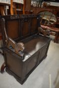 A 20th century Monks bench having carved lion arms with seat storage