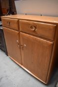 A Ercol sideboard having two drawers over double cupboard, light colour