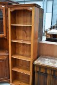 A slim pine bookshelf having four shelves.