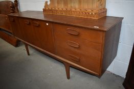 A vintage teak long john style sideboard having triple cupboard and three drawers, stylised legs and