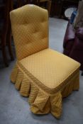 A vintage dressing table chair or nursing chair, having gold upholstery.