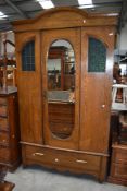 A late Victorian/ Edwardian oak wardrobe having textured green glass and leaded windows two front,