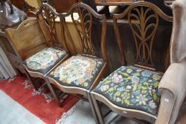 A set of three early 20th Century mahogany dining chairs having wave fronts and drop in tapestry