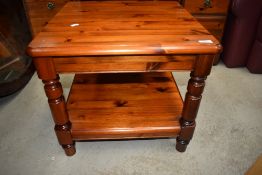 A stained pine coffee table having shelf and turned legs.