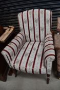 A Victorian easy chair having mahogany turned legs, with later striped upholstery