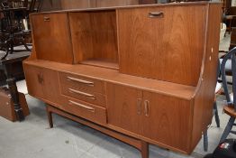 A vintage teak G plan or similar sideboard/cocktail cabinet with drop flap and slide door to top,