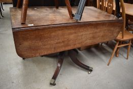 A 19th Century Regency design pedestal table having drop leaf top on turned column and quadruple