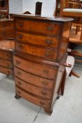 A reproduction bow fronted narrow chest of three over four drawers