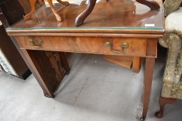 An early 20th Century walnut/mahogany fold over tea table having additional protective glass top,